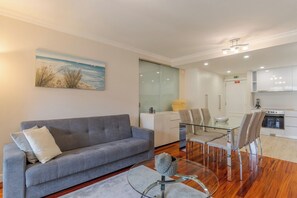 A modern living room with a grey sofa, a glass coffee table, and a dining area with a glass table and chairs. - Stay In Avenue Arriaga 10, by Pausa H. Rentals (Funchal)