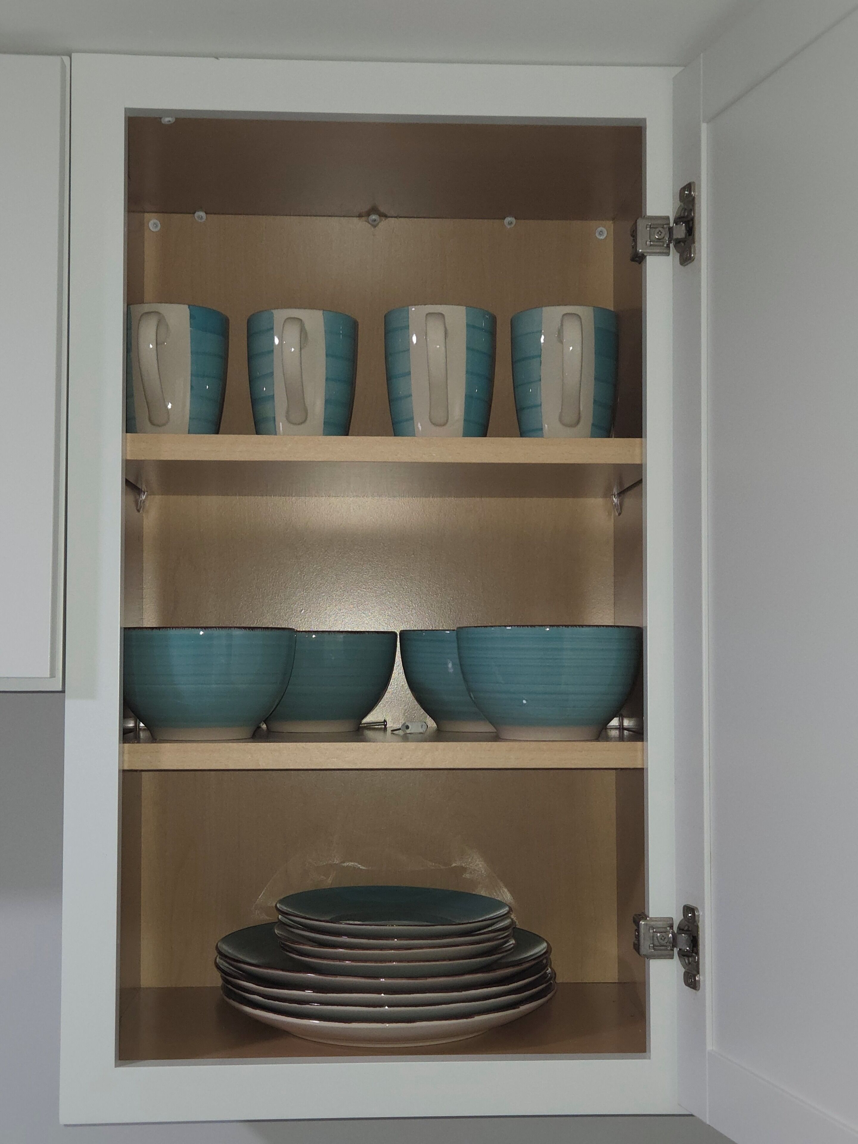Un mueble con estantes que contiene cuencos y platos.