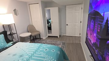 A hotel room with a bed, a desk, a chair, a TV, and a wardrobe.