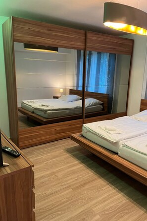 A bedroom with a bed, a mirror, and a nightstand.