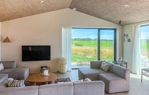 A spacious living room with a large window, a flat-screen TV, and a cozy seating area. - 4 bedroom beautiful home in Haderslev (Haderslev)