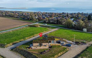 An aerial view of a residential area with houses, a road, and a large green field. - 4 bedroom beautiful home in Haderslev (Haderslev)