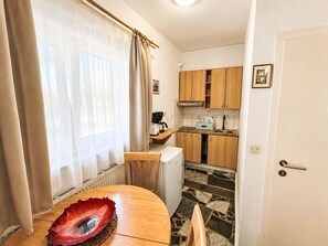 Uma cozinha compacta com armários de madeira, um balcão pequeno e um espaço de refeições com mesa e cadeiras.