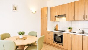 Eine moderne Küche mit Holzschränken, einem runden Esstisch und grünen Stühlen.