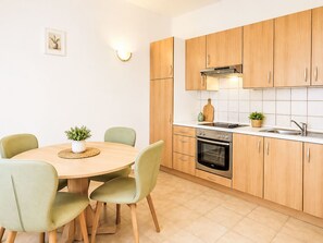 Eine moderne Küche mit Holzschränken, einem runden Esstisch und grünen Stühlen.