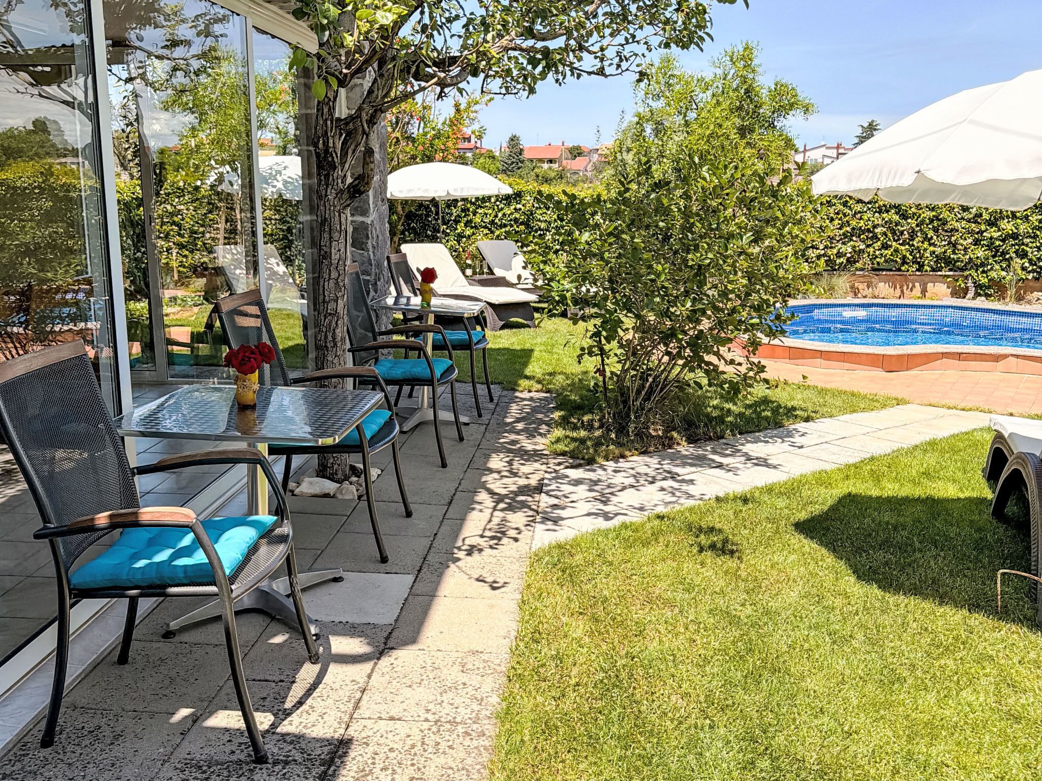Eine Terrasse mit Sitzgelegenheiten im Freien, ein kleiner Baum und ein Schwimmbad.