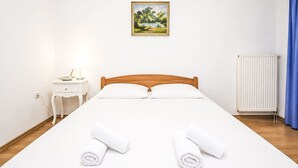 Ein Hotelzimmer mit einem hölzernen Bett, weißen Leinen, einem Nachttisch mit Lampe, einem Bild an der Wand und einer Heizung.