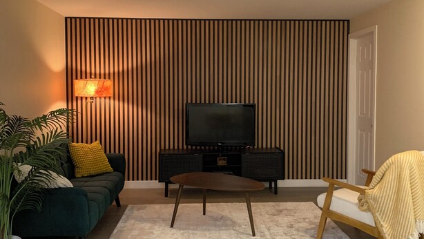 Een moderne woonkamer met een televisie, bank en salontafel.