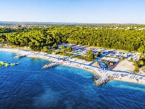 An aerial view of a coastal area with a marina, beach, and surrounding forest. - Ein Apartment im Ferienhaus Zweirosen by Interhome (Fažana)