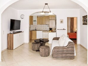 A modern living room with a TV, sofa, ottomans, and a kitchen in the background. - Ein Apartment im Ferienhaus Zweirosen by Interhome (Fažana)