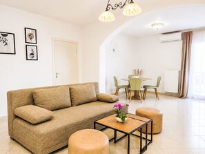 A modern living room with a sofa, ottomans, a coffee table, and a dining area with chairs and a table. - Ein Apartment im Ferienhaus Zweirosen by Interhome (Fažana)