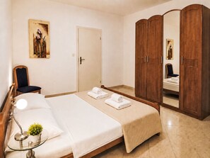 A hotel room with a bed, a chair, a desk with a lamp, a mirror, and a wardrobe. - Ein Apartment im Ferienhaus Zweirosen by Interhome (Fažana)