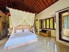 Um quarto espaçoso com uma cama grande, um dossel, um sofá e vista para o verde através de amplas janelas.