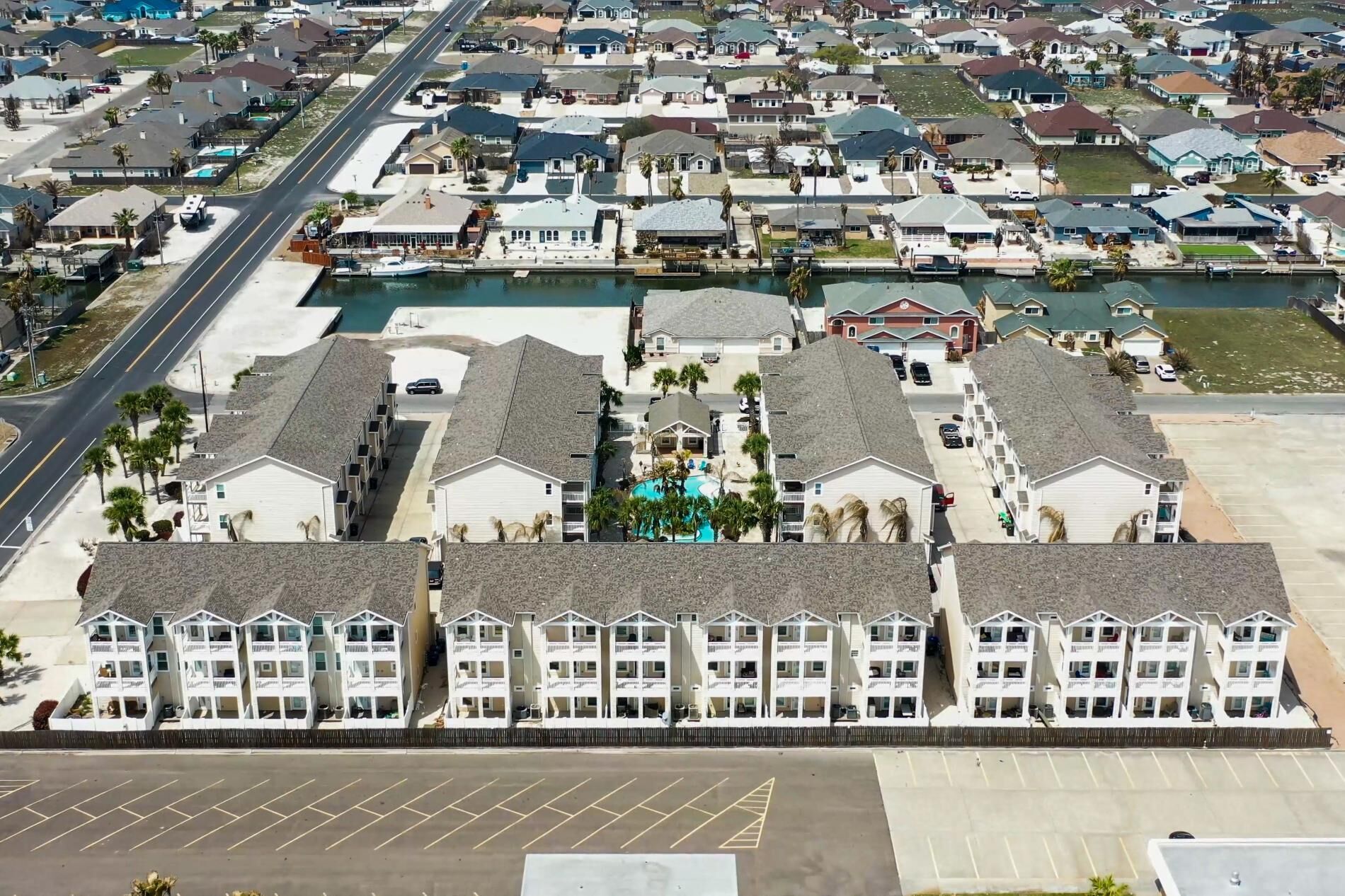 A beachfront hotel with multiple-story buildings, a swimming pool, and a parking lot.