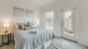 A bedroom with a bed, bedside lamps, a door, and a window. - 3 Bedroom Townhome-Resort Style Pool (Corpus Christi)