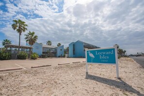A beachfront property named Leeward Isles with a signboard, a covered patio, and a building with a blue exterior.