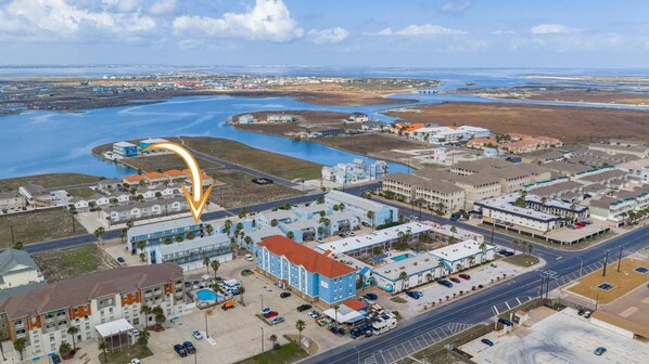 Une ville côtière qui abrite un hôtel imposant, doté d’une piscine et d’un parking.