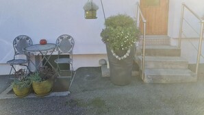 En terrasse med metalsenge og borde, en potteplante og en hængende plantekasse.