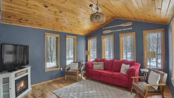 Ein Wohnzimmer mit rotem Sofa, Holzbalkendecke und Kamin.
