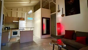 En rummelig opholdsstue med sofa, sofabord og et køkken i baggrunden.