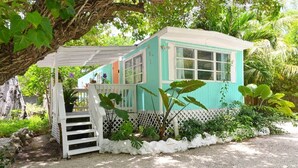 A small, single-story building with a white porch and a turquoise exterior. - The HotTub Hideaway-5 Min From Sombrero Beach (Marathon)