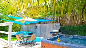 A backyard with a hot tub, outdoor seating, and a grill. - The HotTub Hideaway-5 Min From Sombrero Beach (Marathon)