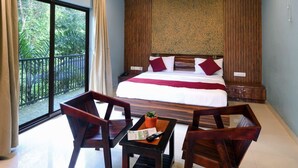 Hotelkamer met een groot bed, een houten hoofdbord, een plafondventilator en een balkon met gordijnen.