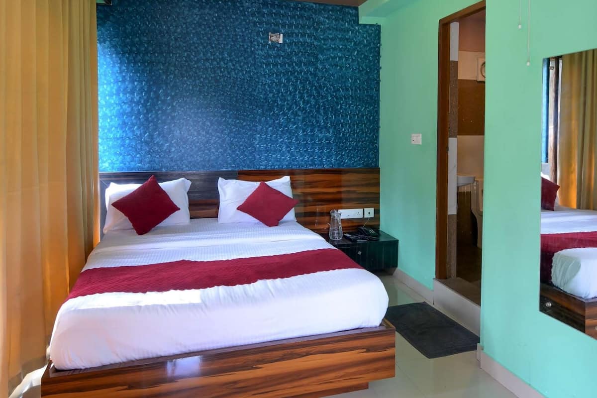 A modern hotel room with a large bed, a wooden headboard, a blue textured wall, and a ceiling fan.