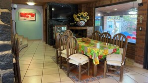 Un coin repas avec une cheminée en briques, un téléviseur fixé au-dessus et une table avec des chaises.