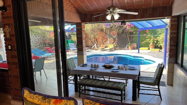 Un espace patio avec une piscine, des sièges d’extérieur et un ventilateur de plafond.