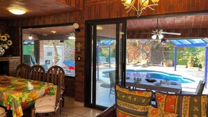 Un espace repas avec vue sur la piscine, des murs en briques et un ventilateur de plafond.