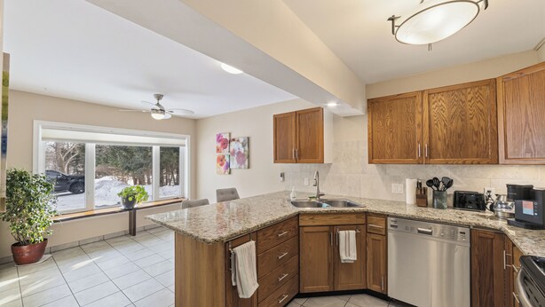 A kitchen with wooden cabinets, a granite countertop, a dishwasher, and a window with a view of the outside. - Total Tranquility Apartment in a country setting. Pet friendly (Brant)