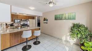 A modern kitchen with wooden cabinets, a granite countertop, and a built-in oven. There are two bar stools and a ceiling fan. - Total Tranquility Apartment in a country setting. Pet friendly (Brant)