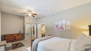 Ein Schlafzimmer mit Bett, Kommode und Deckenventilator.