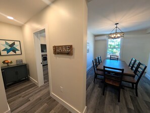 A dining area with a long table and chairs, a chandelier, and a wall-mounted sign.