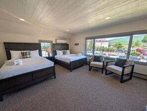 A hotel room with two beds, a window with a view of the parking lot, and a seating area with chairs.
