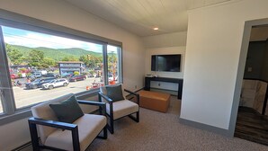 A hotel room with a large window, two armchairs, a TV, and a small seating area. - Village Overlook: Spacious 5 BR + Prime Location (Lake George)