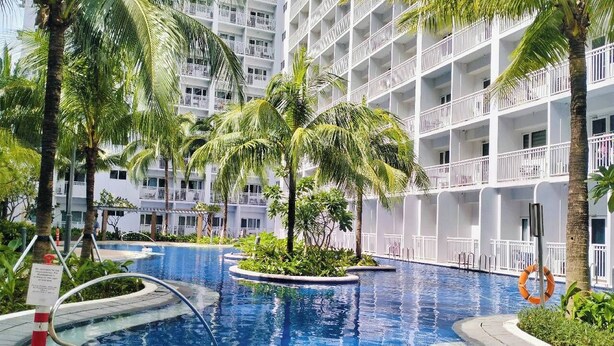 Ein Hotel mit mehreren Balkonen, einem Schwimmbad und Palmen.