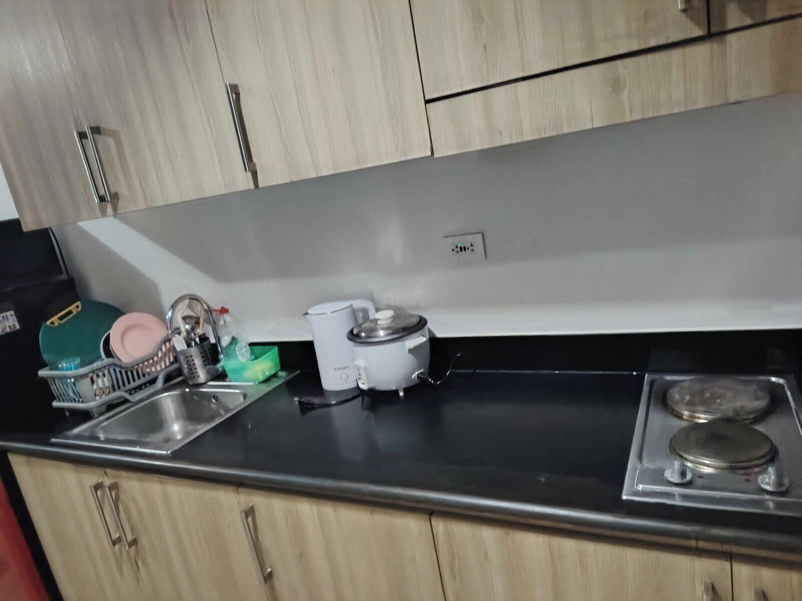 Una cuina amb taulell d'acer inoxidable, una cafetera i un brollador.