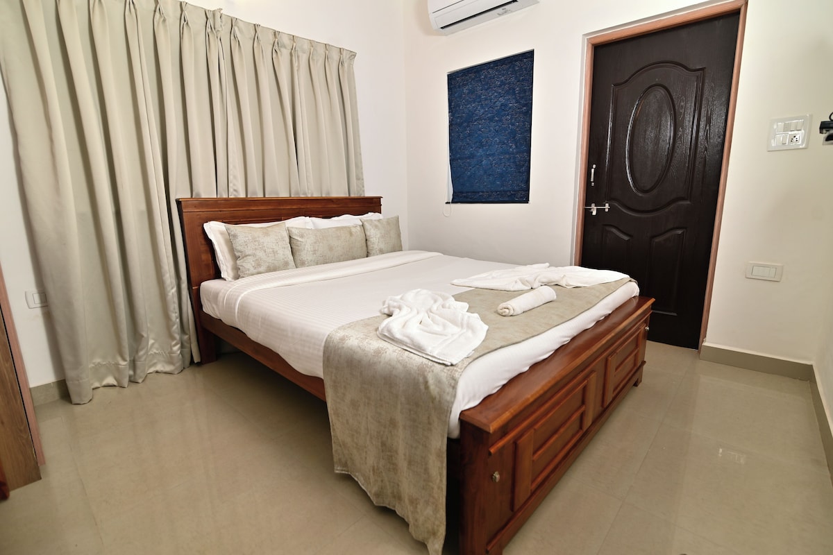 A neatly made bed with a wooden headboard, a beige blanket, and a white pillow.