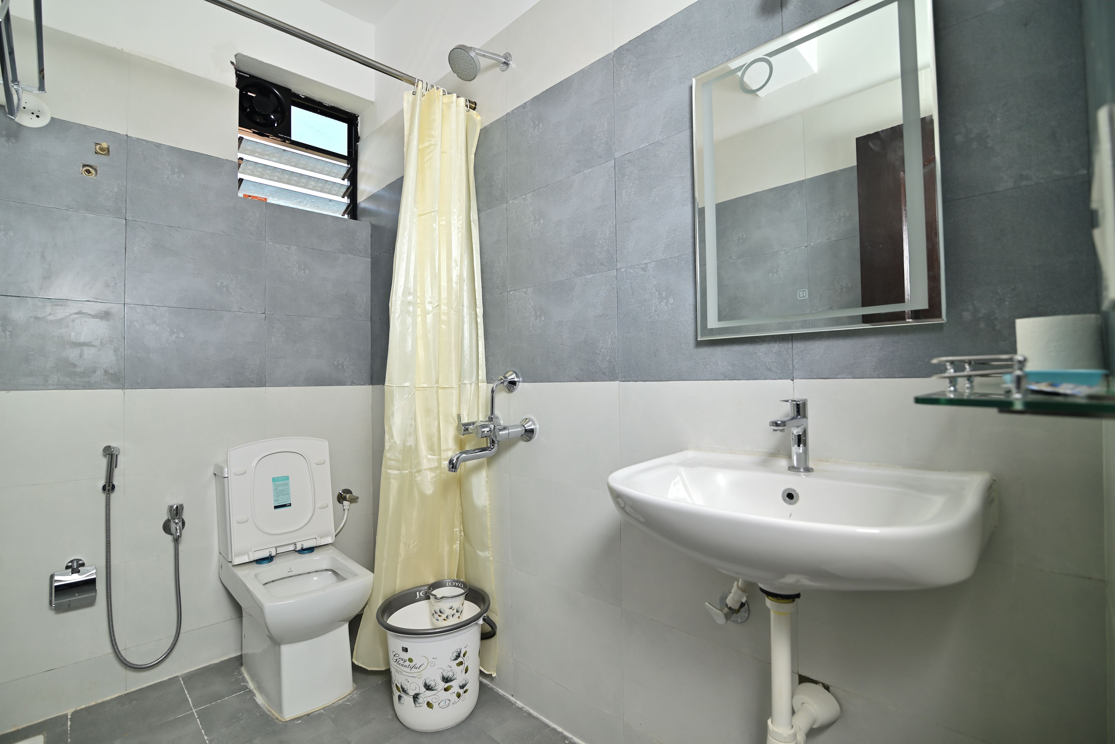 Ein Badezimmer mit Toilette, Bidet, Waschbecken, Dusche und einem Spiegel.