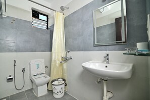 A bathroom with a toilet, bidet, sink, shower, and a mirror.