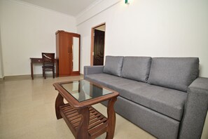 A living room with a grey sofa, a wooden coffee table, and a wooden cabinet.