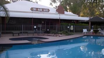 A swimming pool with a covered area and a building with a sign.
