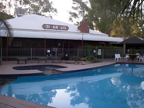 A swimming pool with a covered area and a building with a sign. - Discovery Parks Alice Springs (Alice Springs)
