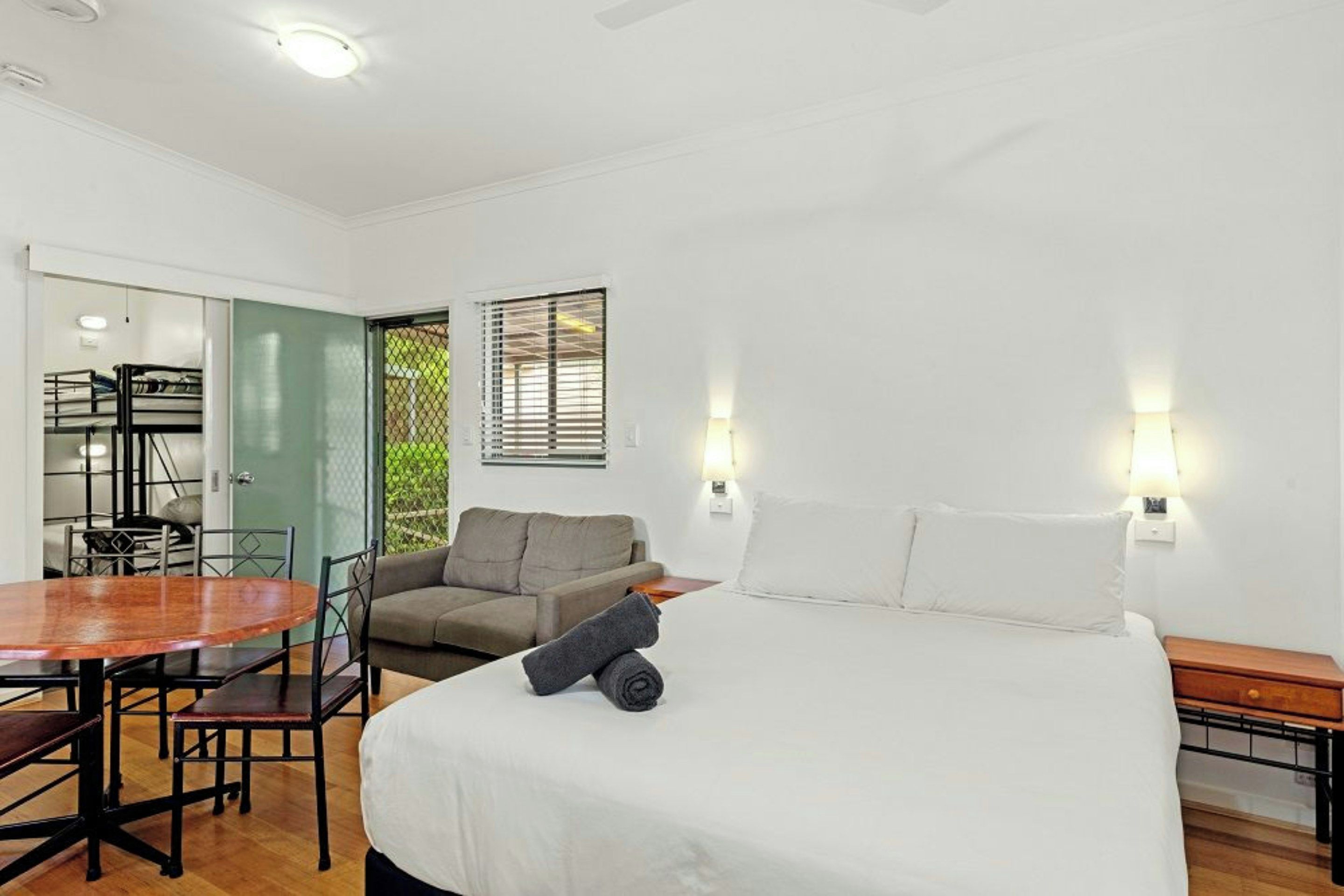 A bedroom with a bed, a desk, a chair, and a sofa.