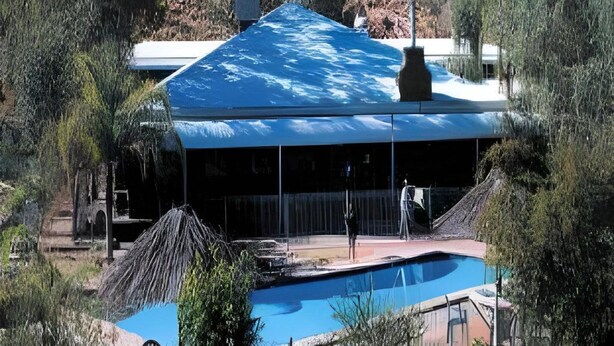 Um edifício com uma piscina grande e uma área coberta.