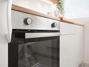 A modern kitchen with a stainless steel range hood, a built-in oven, and a wooden countertop.