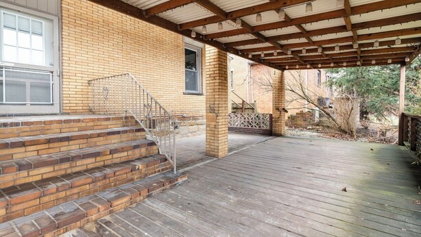 A covered wooden deck with steps leading to a brick building. - Spacious 2BR Apt • Free Parking • Baden (Baden)