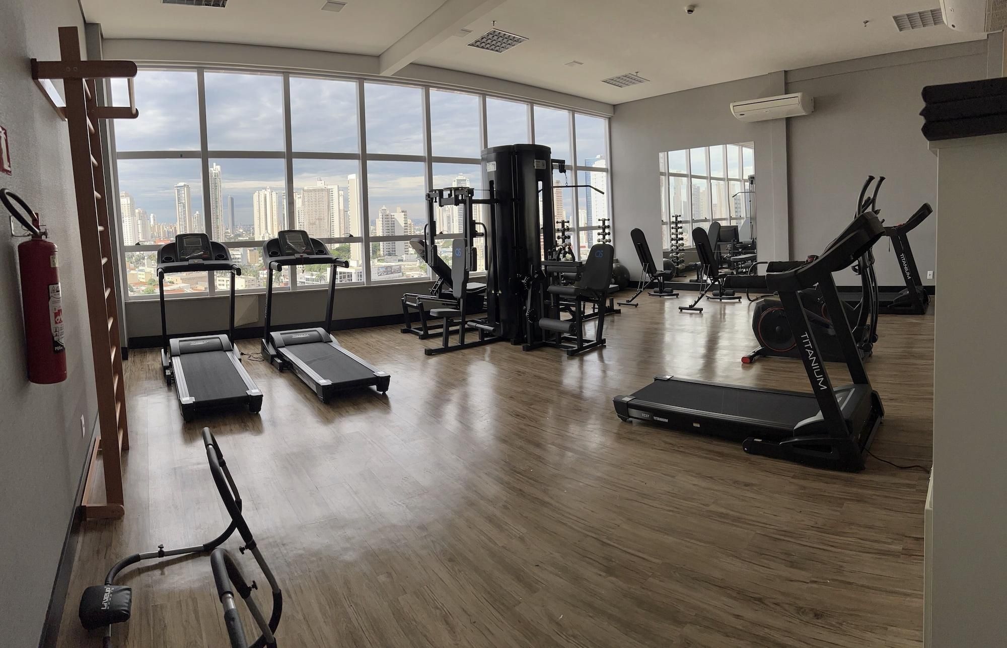 Un gimnasio espacioso con cintas de correr, máquinas de pesas y un amplio ventanal con vistas a la ciudad.